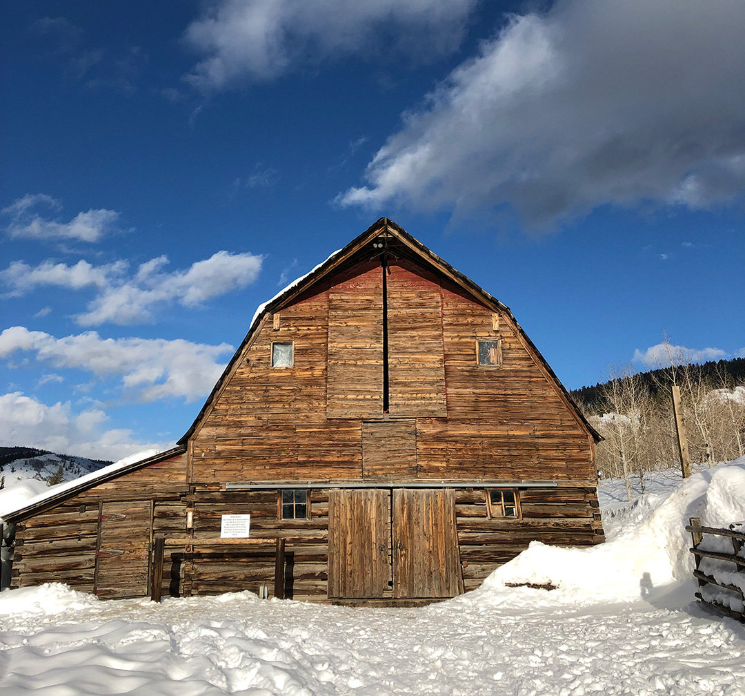 Photo of a barn at The Home Ranch under a blue sky and snow